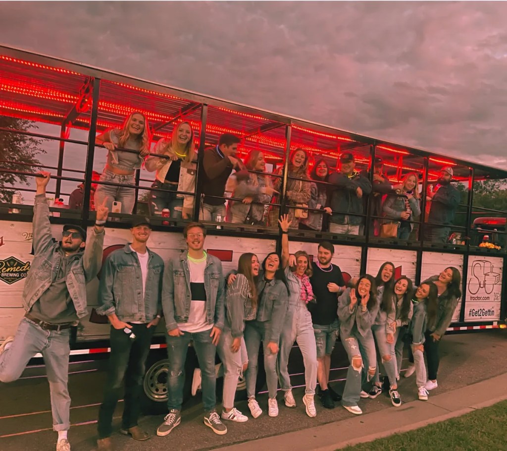 Large group of friends posing outside the SuFu Tractor party wagon in Sioux Falls SD